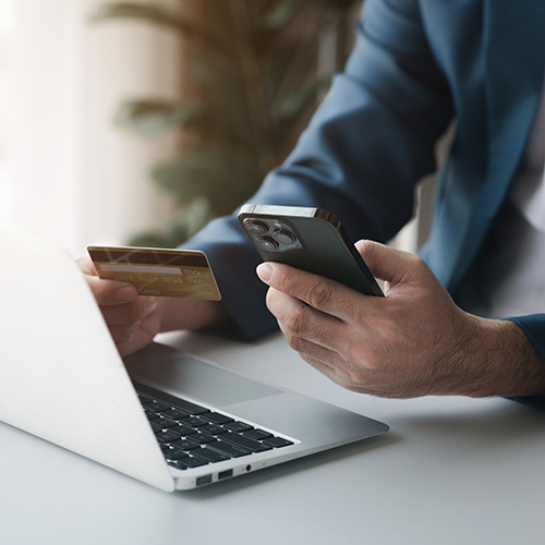 Person holding a credit card, to pay bill online via phone or laptop