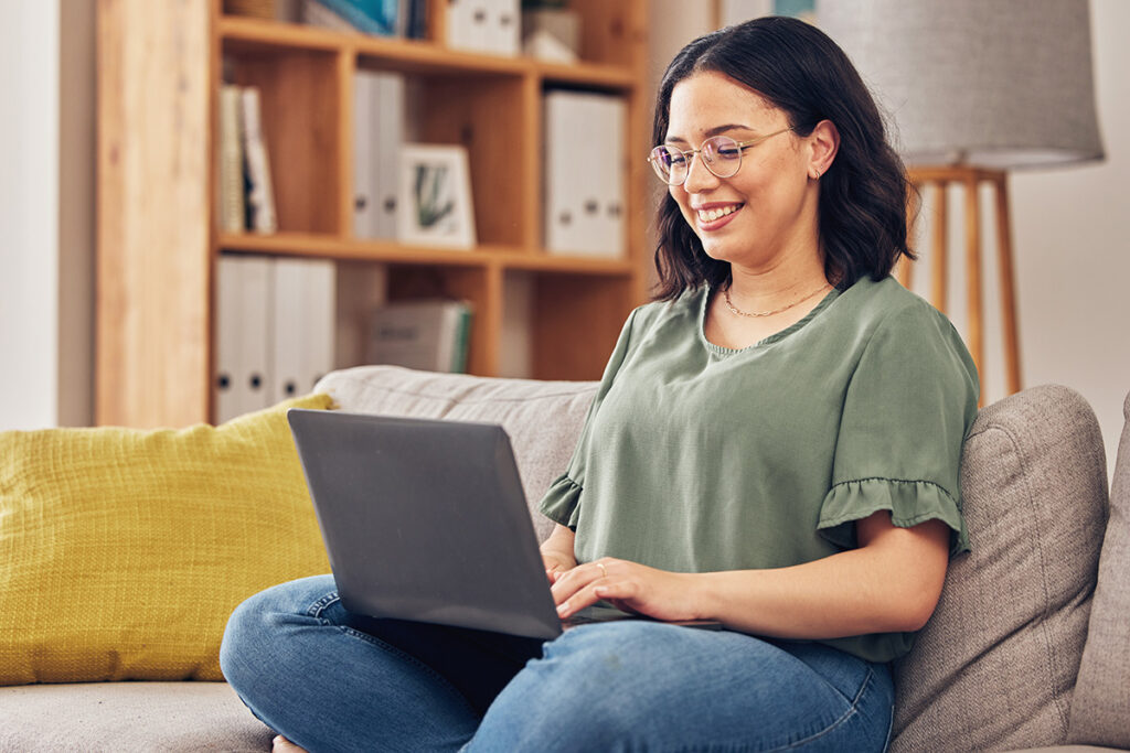 Woman in college on her laptop in her apartment, sitting criss cross