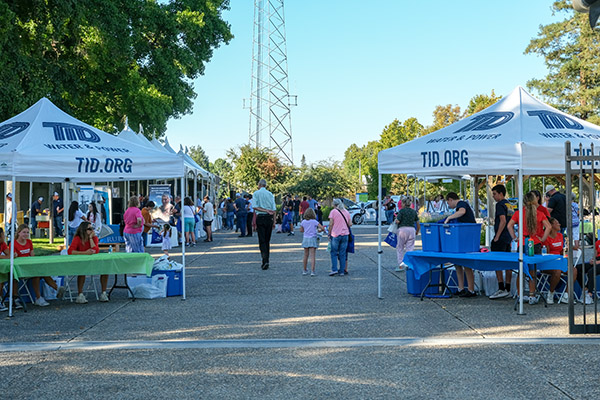 People walk through a community event with TID tents set up.