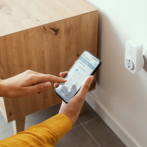 Woman setting a smart plug at home using her smartphone