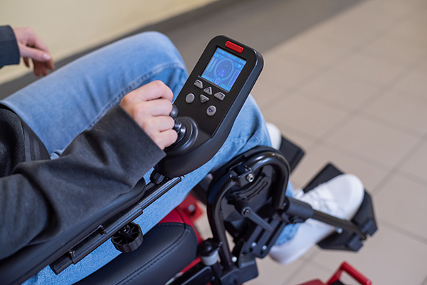 Close-up of a hand on the control handle of an electric wheelchair.