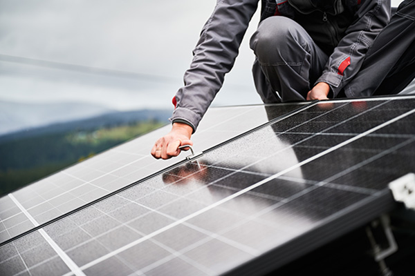 engineer mounting photovoltaic solar panels on roof of house.