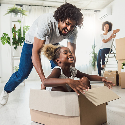 Happy family playing with moving boxes as they move in.