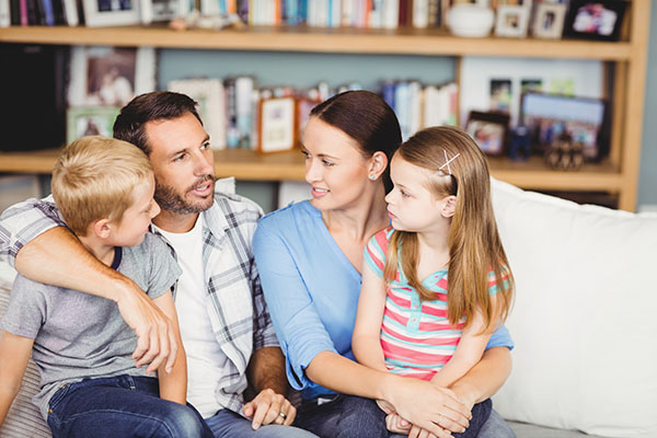 family of four sitting on a couch talking to each other