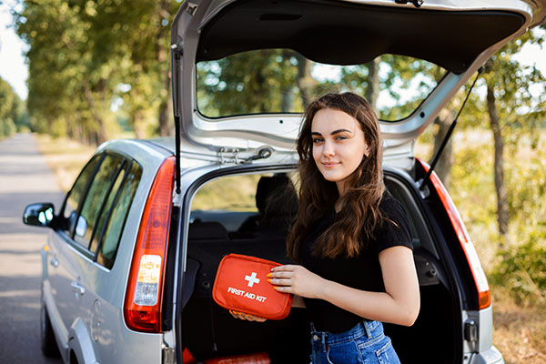 young person grabbing a first aid kit from the back of the car