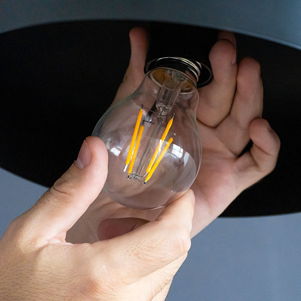 Two hands install lightbulb into light fixture.