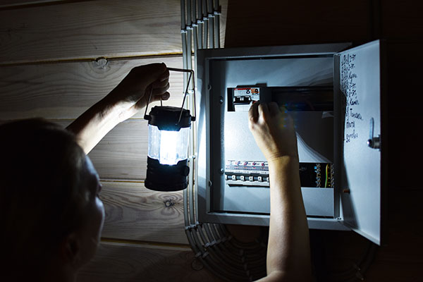 person shining a flashlight toward a breaker box