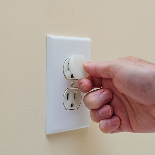 Hand plugs in an electricity safety cover to outlet.