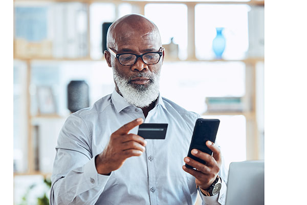 Elderly black man pays his bills on his phone