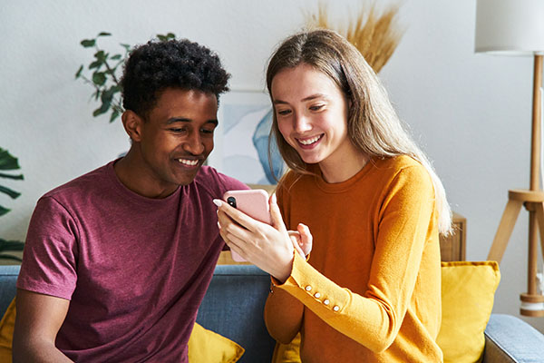 Couple checking the smartphone sitting on the living room couch