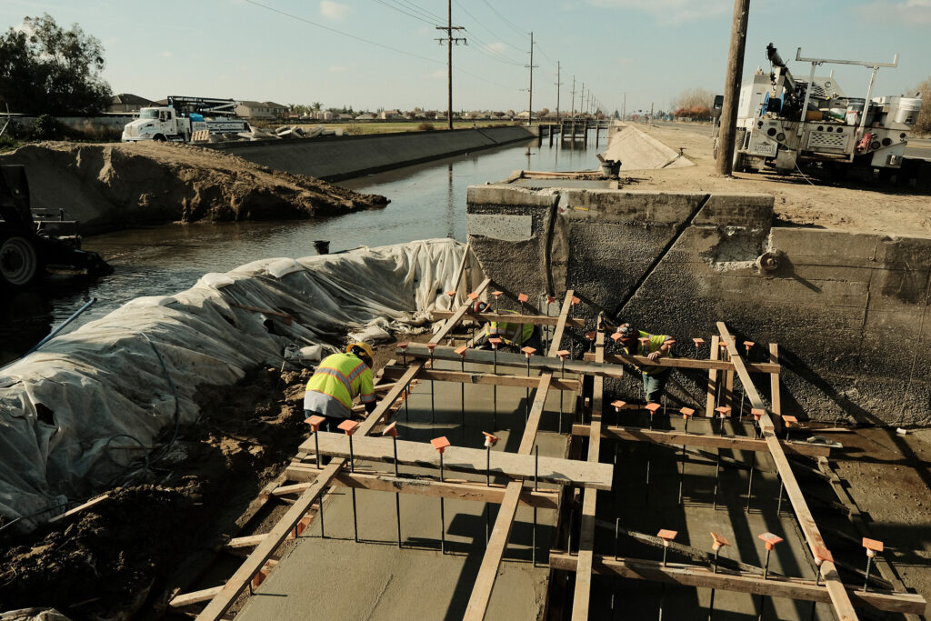Construction and Maintenance workers build drop inside irrigation canal system.