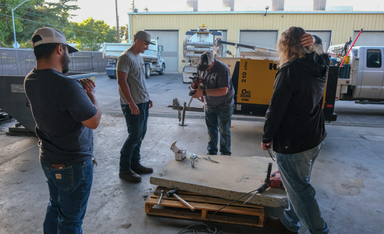 Presenters shows group of three students how to operate a power drill.