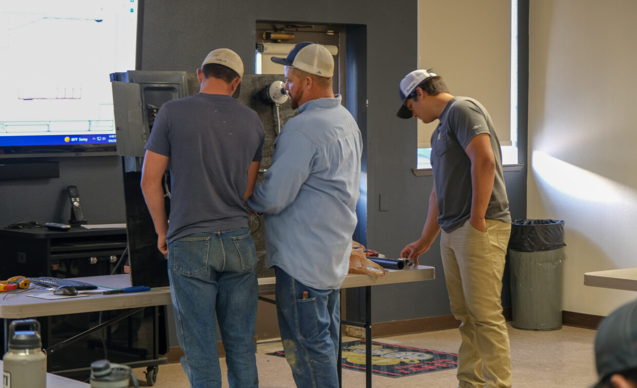 Presenter shows two students how an electrical panel works.